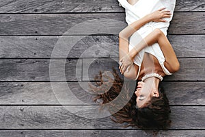 Photo of beautiful lady in white dress laying on the wooden floor,summer accessories.