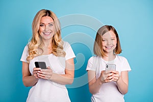 Photo of beautiful mom lady little daughter blonds spend time together hold telephones hands writing new post bloggers