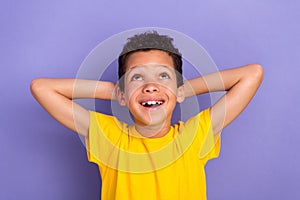 Photo of beautiful positive boy wear stylish clothes hold arms behind head look up empty space promo isolated on purple