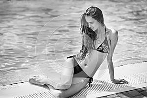 Photo of beautiful woman sitiing near swimming pool