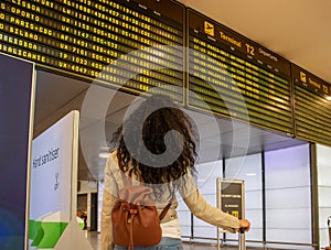 Photo of a beautiful woman traveler looking at the departure board at Adolfo Suarez Madrid-Barajas International Airport