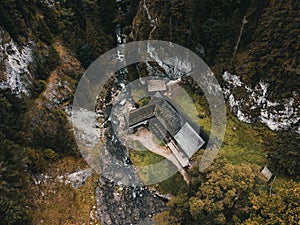 Fotografie krásné dřevěné chaty s řekou v lese shora - Mlyny Oblazy Slovensko - pořízená dronem. Starý dřevěný mlýn