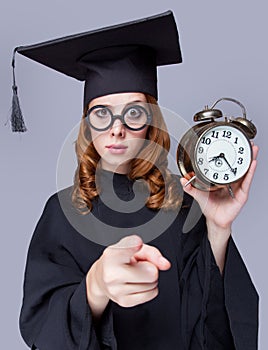 photo of beautiful young alumnus with alarm clock on the wonderful grey studio background photo