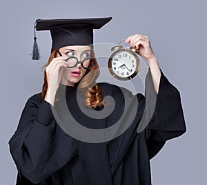 photo of beautiful young alumnus with alarm clock on the wonderful grey studio background