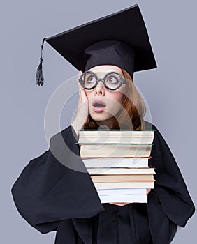 photo of beautiful young alumnus with pile of books on the wonderful grey studio background