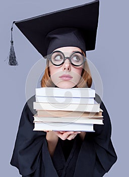 photo of beautiful young alumnus with pile of books on the wonderful grey studio background