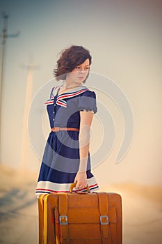 Photo of beautiful young girl standing with suitcase on the road