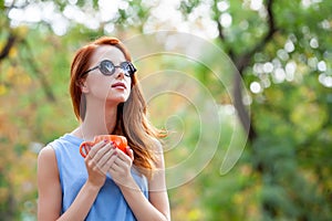 photo of beautiful young woman with cup of coffee on the wonderful autumn park background