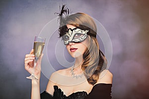 photo of beautiful young woman in mask with wineglass of champagne on the wonderful black studio background