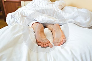 Photo on bed of girls feet lying on pillow