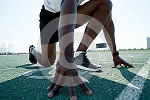 Photo below. African American athlete man preparing for the race at the competition standing at the start