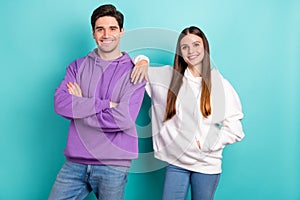 Photo of best friends good buddies in similar hoodies smiling cool cross hands isolated on blue color background