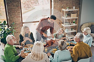 Photo of big family sit feast meals table around holiday roasted turkey father guy making slices hungry relatives