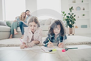 Photo of big family two children comfortable lying floor fluffy carpet making drawings while parents sit sofa