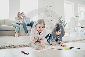 Photo of big family two children lying floor fluffy carpet making drawings while parents enjoy watching friendly adopted