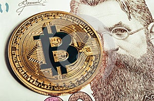 Photo of a bitcoin laying on top of a ukrainian banknote
