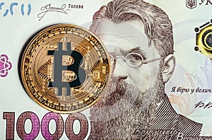 Photo of a bitcoin laying on top of a ukrainian banknote