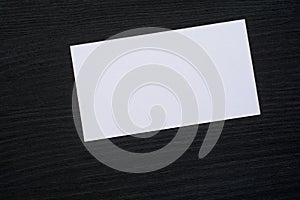 Photo of blank white business cards on a dark wooden background. Mock-up for branding identity.