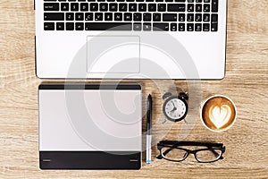Photo blogger / photographer / it specialist`s typical office space table with laptop, blank screen, coffee cup and electronics.