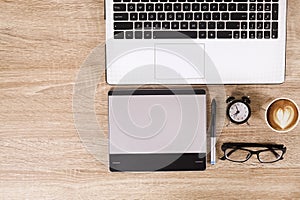 Photo blogger / photographer / it specialist`s typical office space table with laptop, blank screen, coffee cup and electronics.