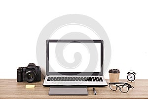 Photo blogger / photographer / it specialist`s typical office space table with laptop, blank screen, coffee cup and electronics.