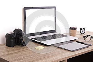 Photo blogger / photographer / it specialist`s typical office space table with laptop, blank screen, coffee cup and electronics.