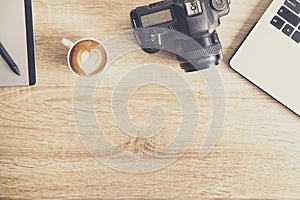 Photo blogger / photographer / it specialist`s typical office space table with laptop, blank screen, coffee cup and electronics.