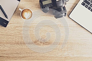 Photo blogger / photographer / it specialist`s typical office space table with laptop, blank screen, coffee cup and electronics.