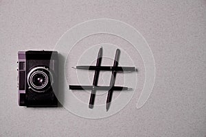 Photo blogging, blog and blogger or social media concept: symbol hashtag and a retro photo camera on a grey background. Flat lay