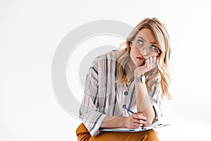 Photo of blond serious woman wearing glasses propping her head and looking upward while sitting