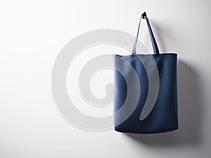 Photo blue cotton textile bag hanging right side. Empty white wall background. Highly detailed texture, space for advertising. Hor