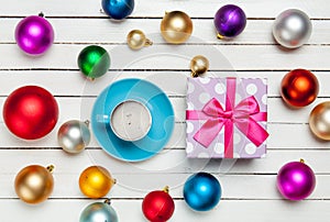 Photo of blue cup of coffee and cute gift near colorful baubles