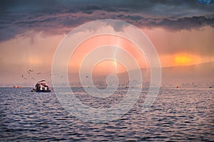 Photo of a boat riding on the local dam with thunderstorm over the horizon.