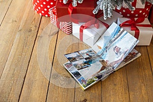 Photo book album under the Christmas tree surrounded by Christmas gifts