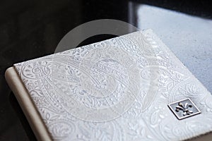 Photo book with a cover of genuine leather. White color with decorative stamping. Wedding or family photo album. Family value