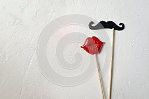 Photo booth props mustache lips on white stone board background.