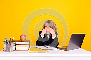 Photo of bored schoolboy sit desk fists cheeks look empty space wear uniform isolated yellow color background