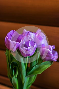 Photo of a bouquet of tulips with lilac petals against wooden background