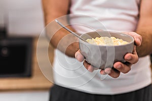 Photo of bowl of corn flakes with milk and spoon inside isolated on blurred background.