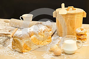 Photo of bread, eggs, milk, donuts and fresh milk on wooden table. Breakfast preparation, daily product