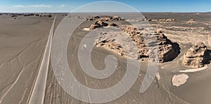 Photo of a breathtaking aerial view of a vast desert landscape with rugged rocks and golden sand dunes