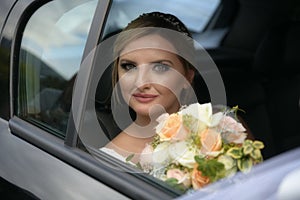 Portrait of happy bride looks out of the car window