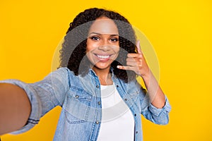 Photo of brunette happy dark skin woman call me sign make selfie good mood isolated on yellow color background