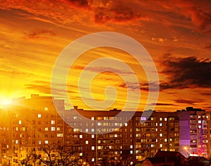 Photo of buildings at night with factory smoke above them with sunset