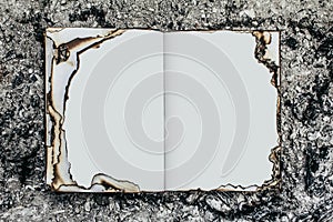 Photo of burned opened book on ashes surface photo