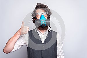 Photo of business man in suit showing thumbs up and wearing respirator