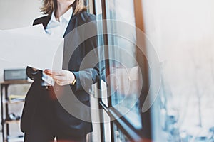 Photo business woman wearing modern suit and holding papers in hands. Open space loft office. Panoramic windows background. Horizo