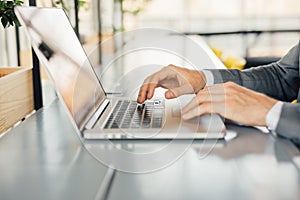 Photo businessman working on modern loft office. Man sitting wood table and using contemporary notebook, texting message keyboard.