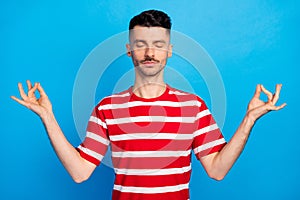 Photo of calm brunette charming relaxed young man make om sign asana isolated on blue color background