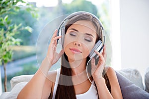 Photo of calm lovely girl closed eyes hands touch headphones enjoy new single pastime indoors